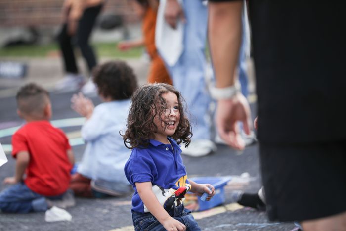 A smiling child plays with sidewalk chalk